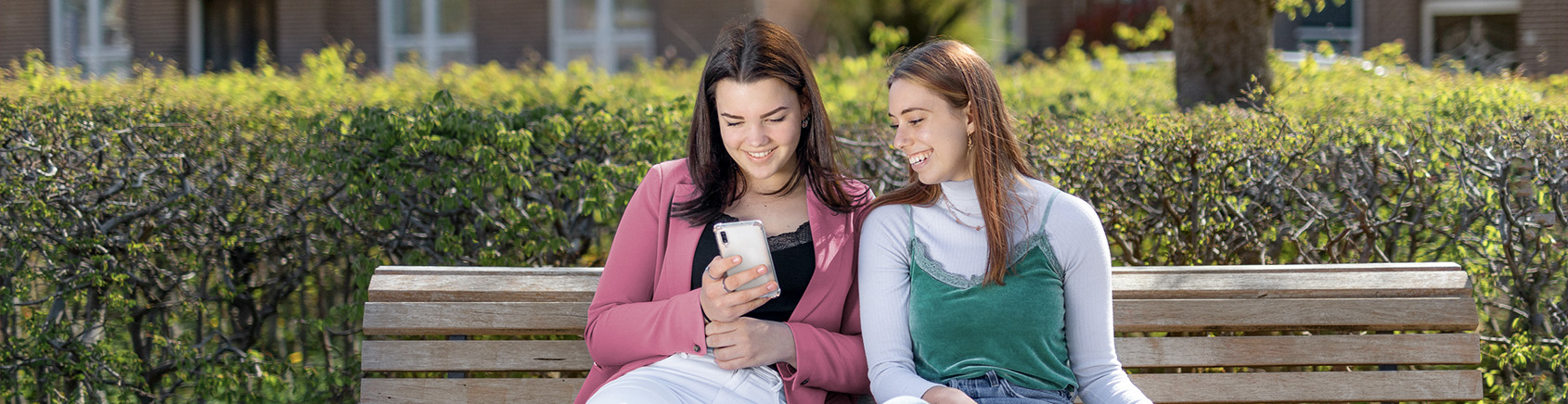 2 jongvolwassenen zitten op een bankje